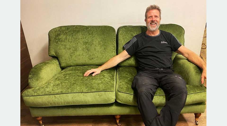 Tapetserare Lars sitter på en grön soffa